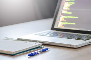 A notebook, a notepad and a pen are lying on a desk.